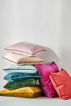 a pile of pillows sitting on top of each other in front of a white wall