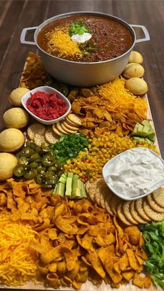 a platter filled with chips, dips and other food on top of a wooden table