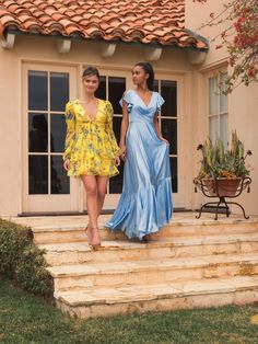 two women in dresses are walking down the steps