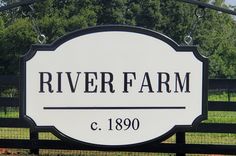 the river farm sign is in front of a black fence and green field with trees