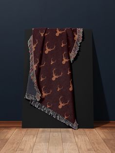 a blanket with deer heads and fringes on it in front of a blue wall