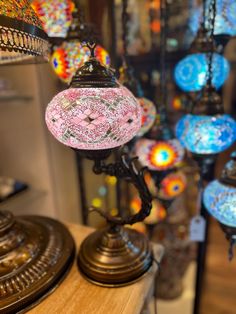 many colorful lights are hanging from the ceiling in a store or shop, with one light turned on