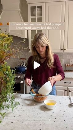 a woman pouring orange juice into a bowl on top of a kitchen counter next to a potted plant