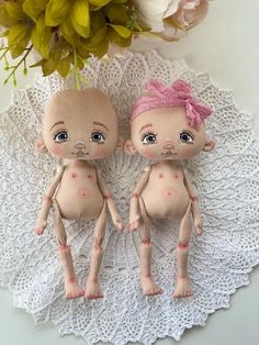 two small dolls sitting on top of a doily