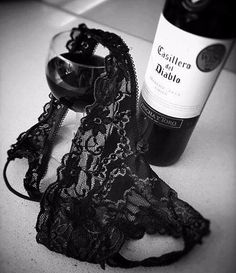 a black lace garter next to a bottle of wine on a counter top,