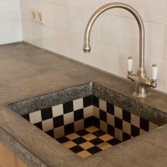 a kitchen sink with a checkerboard design under the faucet and countertop