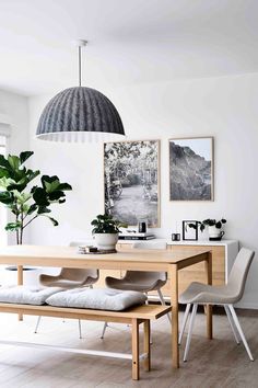 an image of a dining room with white walls and wood furniture in the center, along with pictures on the wall