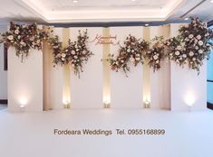 an indoor wedding setup with flowers on the wall and candles in the floor behind it