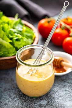 a glass jar filled with dressing next to some vegetables