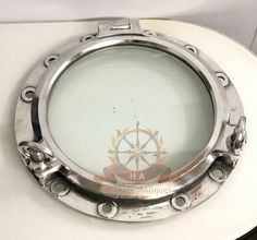 a close up of a metal porthole on the side of a white toilet seat