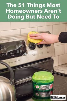 a person is cleaning the stove with a sponge and a bottle of deterant next to it