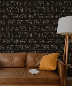 a brown leather couch sitting in front of a black wall with white horses on it