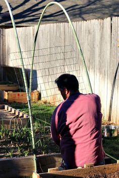 a man kneeling down next to a garden