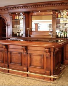 a large wooden bar with lots of bottles on it's shelves and cupboards