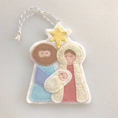 a felt ornament with a nativity scene hanging from it's side