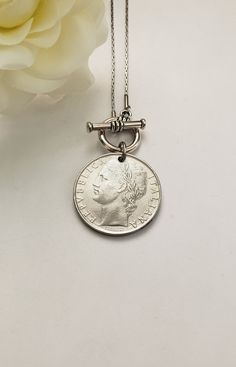 This vintage coin necklace will soon become a favorite go-to necklace. It features an Italian pre-euro silver-tone coin that dangles from an 18" stainless steel chain with a front toggle clasp. Your choice between a 50-lire (24mm or 7/8" in diameter) coin or a 100-lire (27mm or 1" in diameter) coin. Just a beautiful Italian heritage gift! Welcome to Recycled Finery!  I repurpose old jewelry, coins, beads, vintage buttons, watch parts, and charms into new jewelry.  My ever-growing collection of these materials comes from estate sales, rummage sales, antique and thrift stores, and family and friends' collections they no longer need or want. I have fun putting these new pieces together and hope you will find them fun to wear and as unique gifts for your loved ones.     Please note: Because my Elegant Vintage Charm Coin Necklace As Gift, Elegant Vintage Coin Necklace As Gift, Elegant Vintage Charm Coin Necklace For Gift, Elegant Vintage Charm Coin Necklace Gift, Vintage Charm Coin Necklace With Round Pendant As Gift, Classic Coin Necklaces, Vintage Charm Medallion Coin Necklace As Gift, Vintage Charm Medallion Coin Necklace For Gift, Vintage Medallion Coin Necklace As A Gift