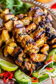 chicken skewers with cucumbers, peppers and onions on a platter