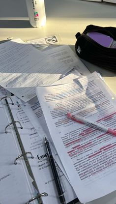 an open notebook and pen sitting on top of a table next to some paper work