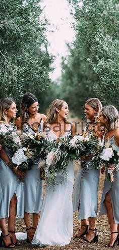 a group of women standing next to each other in front of an olive tree filled field