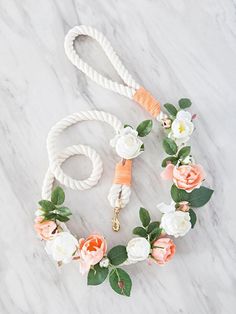 a white rope with pink and white flowers on it, next to a dog leash