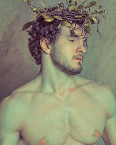 a man with no shirt wearing a crown of leaves on his head and bare chest