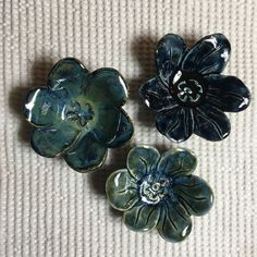 three flower brooches sitting on top of a white cloth covered floor next to each other