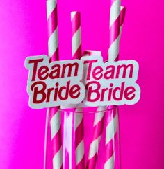 two pink and white striped straws with team bride stickers on them in front of a pink background