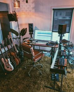 a room filled with musical instruments and a computer monitor on top of a desk in front of a window