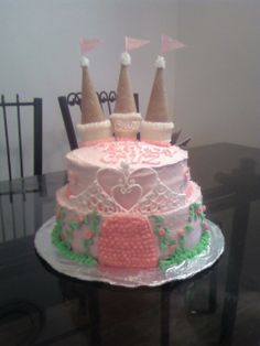 a three tiered cake with pink frosting and white icing, topped with two towers