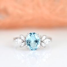 Gorgeous Eva Aquamarine Ring ►Made of solid sterling silver with rhodium finish (925) ►Accented with simulated diamonds (CZ) ►Average band width: 1.8 mm Center Stone: Aquamarine Stone Creation: Created (can be made with a natural aquamarine at additional cost) Stone Cut: Oval Gem size: 7.0 x 9.0 mm Carat Weight: 1.4 ct. (approx.) ✓ 100% Nickel-Free ✓ Hypoallergenic ✓ Comfort Fit ✓ Free Ring Box ✓ Free USA Shipping ✓ Ready to ship next business day Aquamarine Diamond Ring For Anniversary, Anniversary Cluster Ring With Center Stone And Blue Topaz, Light Blue Jewelry With Center Stone For Wedding, Classic Blue Crystal Wedding Ring, Aquamarine Rings With Prong Setting For Anniversary, Blue Birthstone Cluster Ring For Wedding, Blue Topaz Cluster Ring For Wedding, Light Blue Oval Rings For Anniversary, Elegant Light Blue Birthstone Ring For Wedding