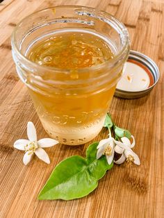 a jar of honey sitting on top of a wooden table next to a spoon and flower