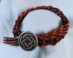 a close up of a bracelet on a white cloth with a metal clasp and knot