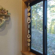 a window sill with shells hanging from it's side next to a potted plant