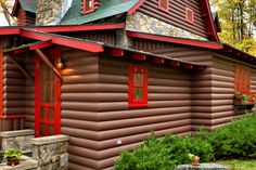 a log cabin with red trim and windows