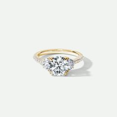 a three stone engagement ring with diamonds on the sides and an accent band in yellow gold