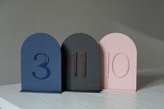 three small wooden numbers sitting on top of a white counter next to each other in front of a gray wall