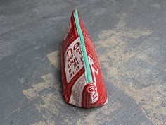 a small red and white bag sitting on top of a cement floor next to a green zipper