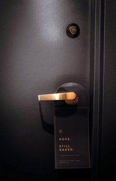 a black door with a gold handle and name tag hanging on it's side