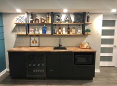 a bar with lots of bottles and liquor on the shelves above it, along with a sink