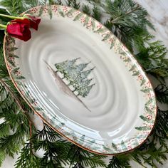 a plate with a christmas tree on it and a red rose in front of it