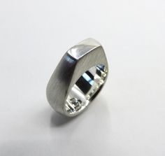 A heavy sterling silver ring in the style of mid century modern Scandinavian design. A beautiful tapered geometric design, polished top surface against a satin brushed finish to highlight the clean lines of the piece. Very much in the atomic style of artisans from the 50s & 60s. Ring sizes are limited because of the design. Dimensions of ring: Weight 19 grams  Rectangle height 5mm Rectangle width 10mm Back of ring width 12mm Please check out my other designs and vintage pieces here: https://www. Modern Dome Ring For Anniversary, Modern Polished Concave Signet Ring, Modern Wide Band Ring With Polished Edges, Modern Silver Signet Ring, Modern Sterling Silver Dome Ring, Modern Silver Signet Ring With Polished Edges, Modern Silver Wide Band Ring For Anniversary, Modern Dome Ring With Polished Edges For Gifts, Modern Dome Ring With Polished Edges For Anniversary