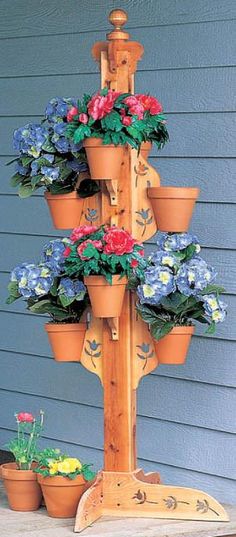 a wooden pole with potted plants on it and flowers growing out of the top