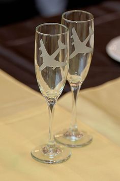 two wine glasses sitting on top of a table next to each other with an airplane drawn on them