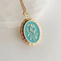 Introducing our stunning oval locket with an embossed hibiscus flower design - a truly unique and charming piece of jewelry. Crafted from high-quality gold plated brass, this locket has a bright, shiny finish and a detailed flat backside that gives it a sophisticated look. Measuring 30mm tall and 23mm wide, this medium-sized locket is perfect for everyday wear. It opens up to reveal a secret place where you can store your most cherished photos, messages, or any other keepsake that holds a specia Vintage Charm Locket Necklace With Flower Pendant For Gift, Vintage Medallion Jewelry With Flower Charm, Cameo Oval Pendant Locket Necklace Gift, Oval Cameo Locket Necklace Gift, Cameo Locket Necklace As Gift, Oval Cameo Necklace Keepsake, Oval Cameo Necklace For Keepsake, Keepsake Flower Charm Locket Necklace, Vintage Flower Jewelry Keepsake