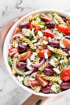 a white bowl filled with pasta salad on top of a marble counter