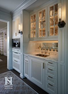 a kitchen with white cabinets and marble counter tops, along with an area rug on the floor