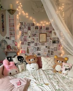 two stuffed animals sitting on top of a bed in front of a wall covered with pictures