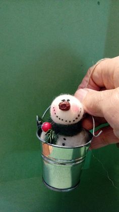 a hand holding a small tin can with a snowman decoration