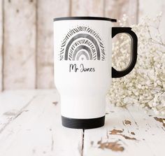 a white and black coffee mug with the words mr jones on it next to some flowers