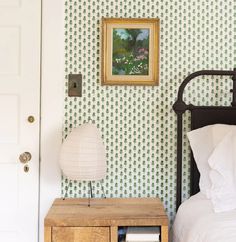 a bed room with a neatly made bed and a painting on the wall